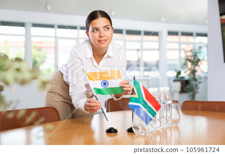 Young lady sets miniatures flags of South Africa and India for international negotiations 105961724