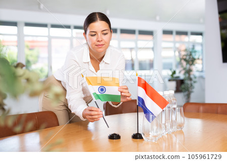 Young lady sets miniatures flags of Netherlands and India for international negotiations Young lady sets miniatures flags of Netherlands and India for international negotiations 105961729