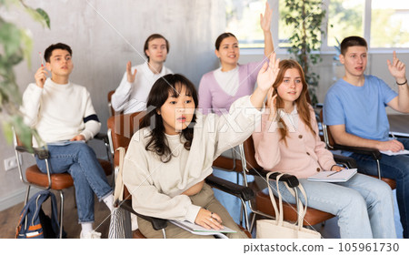 Group of high school students raising hands in auditorium Group of high school students raising hands in auditorium 105961730
