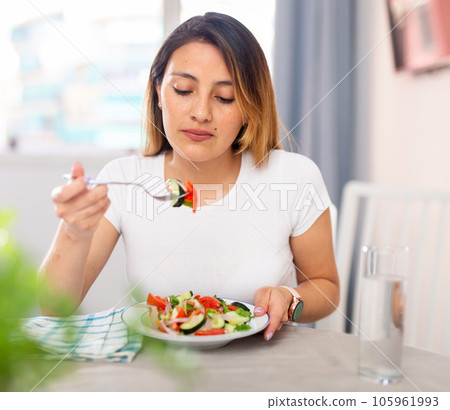 Portrait of positive latino woman tasting fresh green salad with pleasure Portrait of positive latino woman tasting fresh green salad with pleasure 105961993