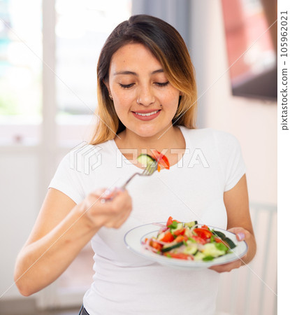 Colombian housewife eating vegetable salad at table at home Colombian housewife eating vegetable salad at table at home 105962021
