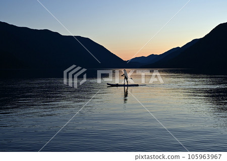 Silhouetted female paddleboarder on Lake Crescent in Olympic National Park. Silhouetted female paddleboarder on Lake Crescent in Olympic National Park. 105963967