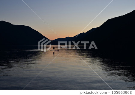 Silhouetted female paddleboarder on Lake Crescent in Olympic National Park. Silhouetted female paddleboarder on Lake Crescent in Olympic National Park. 105963968