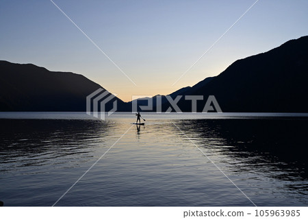 Silhouetted male paddleboarder on Lake Crescent in Olympic National Park. Silhouetted male paddleboarder on Lake Crescent in Olympic National Park. 105963985