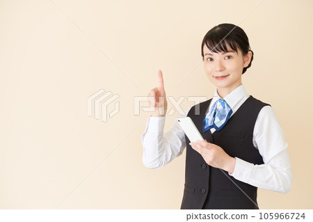 A woman in reception and clerical work wearing a uniform with a ribbon tie on a vest to operate a smartphone A woman in reception and clerical work wearing a uniform with a ribbon tie on a vest to operate a smartphone 105966724