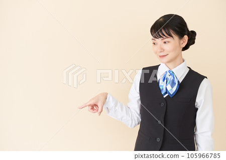 A woman in reception work and clerical work wearing a ribbon tie uniform on a vest pointing with a finger A woman in reception work and clerical work wearing a ribbon tie uniform on a vest pointing with a finger 105966785