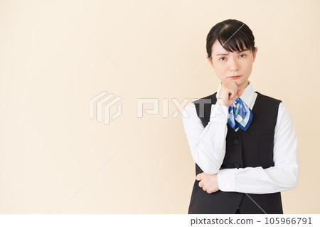 一位從事接待和文書工作的女性,穿著背心上的絲帶領帶制服,擺出思考的姿勢 一位從事接待和文書工作的女性,穿著背心上的絲帶領帶制服,擺出思考的姿勢 105966791