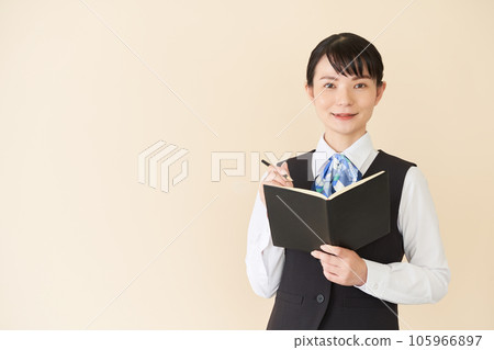 一位從事接待和文書工作的女性,背心上穿著絲帶制服,用於寫筆記本 一位從事接待和文書工作的女性,背心上穿著絲帶制服,用於寫筆記本 105966897
