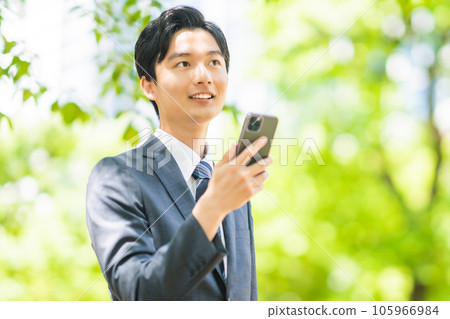 一位年輕商人一隻手拿著智能手機四處走動 105966984
