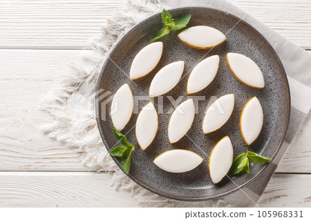 Provencal french Calisson sweets from melon, almond and orange covered with white royal icing close-up in a plate. Horizontal top view Provencal french Calisson sweets from melon, almond and orange covered with white royal icing close-up in a plate. Horizontal top view 105968331