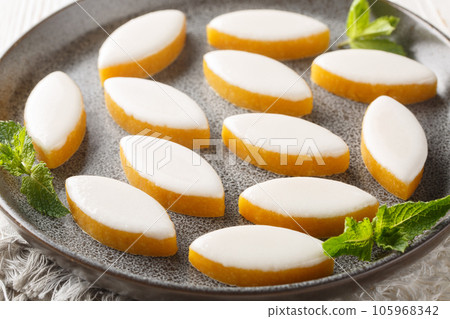 Provencal french Calisson sweets from melon, almond and orange covered with white royal icing close-up in a plate. Horizontal 105968342