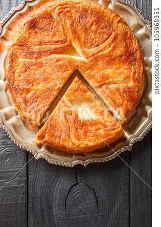 Kouign-amann a sweet Breton cake made with laminated dough closeup on the plate on the table. Vertical top view Kouign-amann a sweet Breton cake made with laminated dough closeup on the plate on the table. Vertical top view 105968351