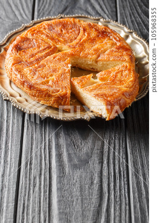 Kouign amann is a round multi-layered cake containing with laminated dough soaked in butter and sugar closeup on the plate. Vertical 105968355