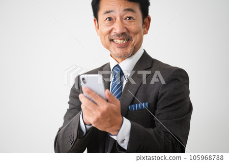 Business image of a middle-aged man operating a smartphone with a smile Business image of a middle-aged man operating a smartphone with a smile 105968788
