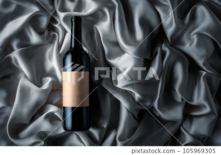 Bottle of red wine with an empty label on a satin background. 105969305