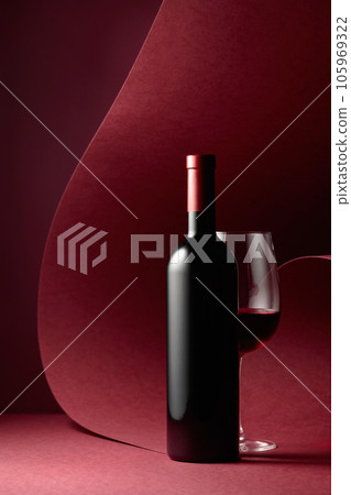 Bottle and glass of red wine on a red background. 105969322