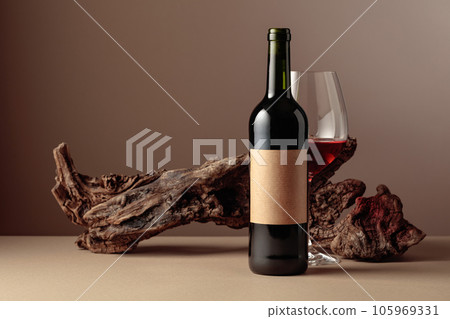Bottle and glass of red wine with old weathered snag. 105969331