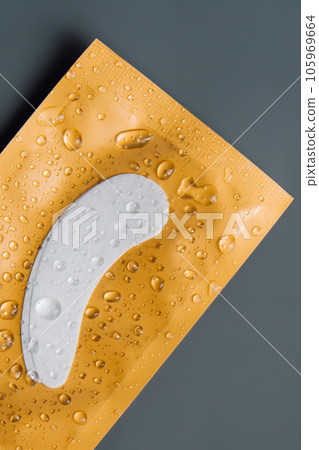 View from above of fresh eyelash extension patches lying on wrapping covered with drops of water, left on desk. View from above of fresh eyelash extension patches lying on wrapping covered with drops of water, left on desk. 105969664