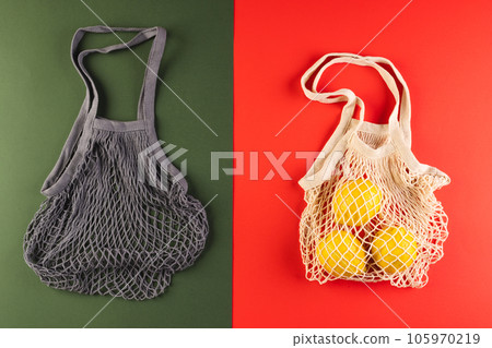 Brown and white mesh net bags with lemons and copy space on red and dark green background Brown and white mesh net bags with lemons and copy space on red and dark green background 105970219