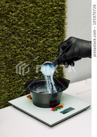 A hairdresser pours an oxidizer. The process of preparation before coloring hair A hairdresser pours an oxidizer. The process of preparation before coloring hair 105970726