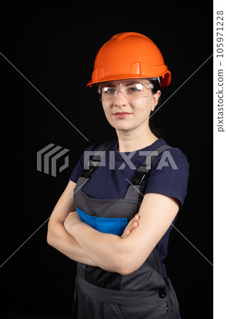 A woman in a protective helmet and overalls on a black background 105971228