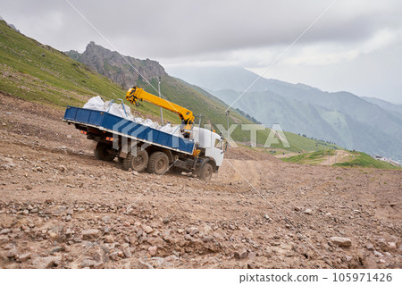 Construction Work in the highlands. Transportation by dump manipulator trucks. Transport industry. Truck is driving along a mountain road. Construction Work in the highlands. Transportation by dump manipulator trucks. Transport industry. Truck is driving along a mountain road. 105971426