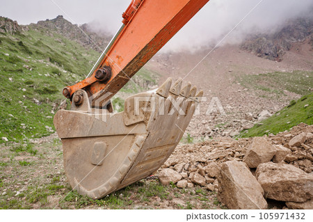 Excavator works in the highlands. Clears the consequences of a mudslide in the gorge of the mountains. repair and expansion of a road 105971432