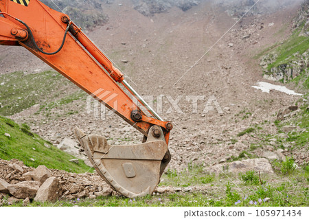 Excavator works in the highlands. Clears the consequences of a mudslide in the gorge of the mountains. repair and expansion of a road 105971434