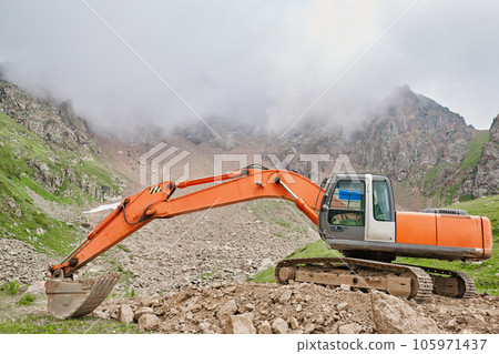 Excavator works in the highlands. Clears the consequences of a mudslide in the gorge of the mountains. repair and expansion of a road 105971437