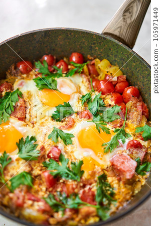 Shakshouka for breakfast. Homemade shakshuka, fried eggs, onion, bell pepper, tomatoes and parsley in a pan. Marble background. Top view. chakchouka Shakshouka for breakfast. Homemade shakshuka, fried eggs, onion, bell pepper, tomatoes and parsley in a pan. Marble background. Top view. chakchouka 105971449
