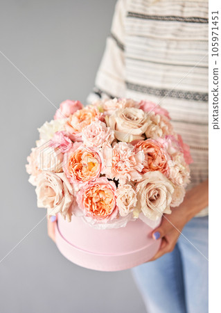 Florist woman creates flower arrangement in a round box. Beautiful bouquet of mixed flowers. Floral shop concept . Handsome fresh bunch. Flowers delivery Florist woman creates flower arrangement in a round box. Beautiful bouquet of mixed flowers. Floral shop concept . Handsome fresh bunch. Flowers delivery 105971451