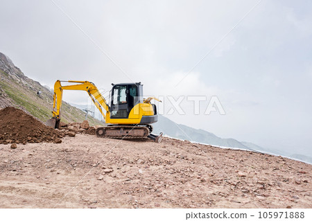 Excavator works in the highlands. Makes a trench for communications. water and electricity. in the gorge of the mountains. repair and expansion of a road 105971888