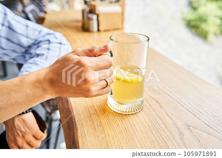 Cup of ginger root tea with lemon, honey and mint on a wooden table and High-mountain river in the background. Walk in the mountains and relax in a cozy cafe. Hiking on a day off 105971891