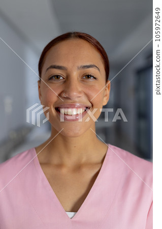 Portrait of happy biracial female doctor wearing scrubs in corridor at hospital Portrait of happy biracial female doctor wearing scrubs in corridor at hospital 105972649