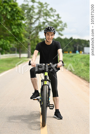 Full length male cyclist in sport clothing and helmet riding bicycle on the road. Sport, active life and healthy lifestyle concept. 105973200