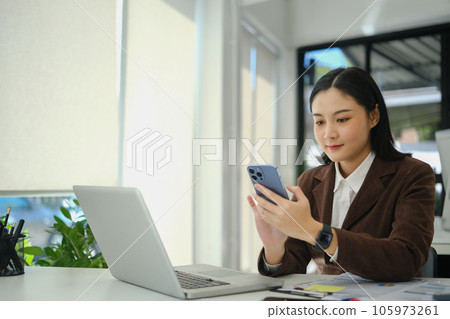 Beautiful young businesswoman texting message, communicating online on mobile phone Beautiful young businesswoman texting message, communicating online on mobile phone 105973261