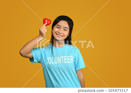 Teenager asian girl wearing volunteer t-shirt isolated on yellow background. Charity, support, altruism and donation concept Teenager asian girl wearing volunteer t-shirt isolated on yellow background. Charity, support, altruism and donation concept 105973317