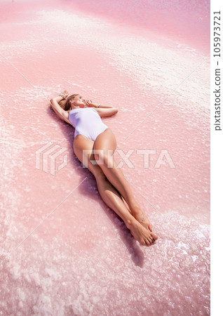 Woman pink salt lake. She lies in a white bathing suit. Wanderlust photo for memory 105973721