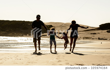 Happy family with children silhouette at sea beach sunset. Father, mother and kids walking on seashore with evening sun light 105974164
