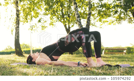 Athletic fitness girl doing an exercises on a mat on a grass Outdoors, body health concept 105974292