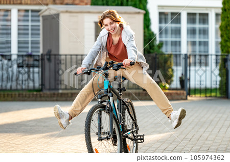 Funny girl riding a bike in the evening in a calm city. Young girl joking and having fun. Eco-friendly urban transport. Funny girl riding a bike in the evening in a calm city. Young girl joking and having fun. Eco-friendly urban transport. 105974362