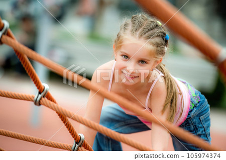 Happy beautiful little girl playing at the playground and climb the ropes outdoor Happy beautiful little girl playing at the playground and climb the ropes outdoor 105974374