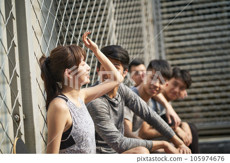 hipster young asian adults resting outdoors at a basketball court after exercise hipster young asian adults resting outdoors at a basketball court after exercise 105974676