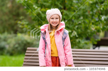 Pretty school girl kid with backpack smiling at autumn park. Beautiful female child portrait with blurred background 105974946