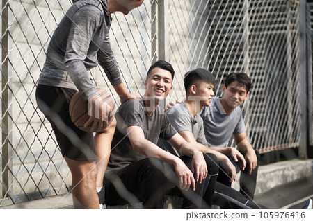 group of four asian young adult men resting relaxing talking chatting on outdoor basketball court 105976416