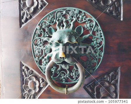 A door knocker is a fixture on the front door of a house. It is made of metal and has the form of a ring, which is knocked on the metal part of the door knocker fixed to the wall. Muzzle of a lion. A door knocker is a fixture on the front door of a house. It is made of metal and has the form of a ring, which is knocked on the metal part of the door knocker fixed to the wall. Muzzle of a lion. 105977341