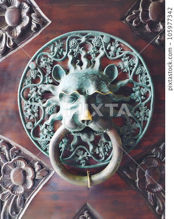 A door knocker is a fixture on the front door of a house. It is made of metal and has the form of a ring, which is knocked on the metal part of the door knocker fixed to the wall. Muzzle of a lion. 105977342