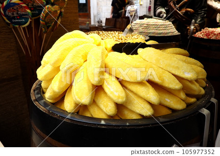 Eclairs in the form of yellow bananas on a dish. Showcase of candy store Dubrovnik Croatia. Delicious sweet cakes are displayed for sale to tourists. Unusual form of baking with powdered yellow sugar Eclairs in the form of yellow bananas on a dish. Showcase of candy store Dubrovnik Croatia. Delicious sweet cakes are displayed for sale to tourists. Unusual form of baking with powdered yellow sugar 105977352