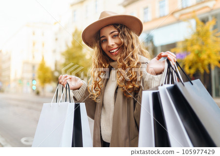 Happy woman with shopping bags walking on street. Purchases, black friday, discounts, sale concept. 105977429