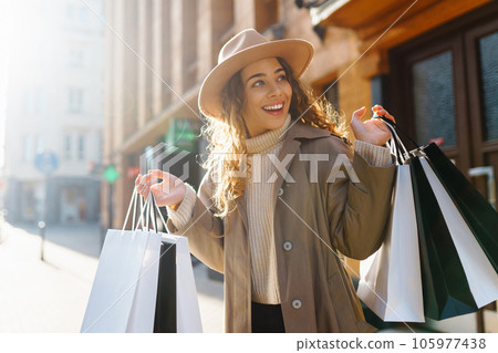 Happy woman with shopping bags walking on street. Purchases, black friday, discounts, sale concept. 105977438